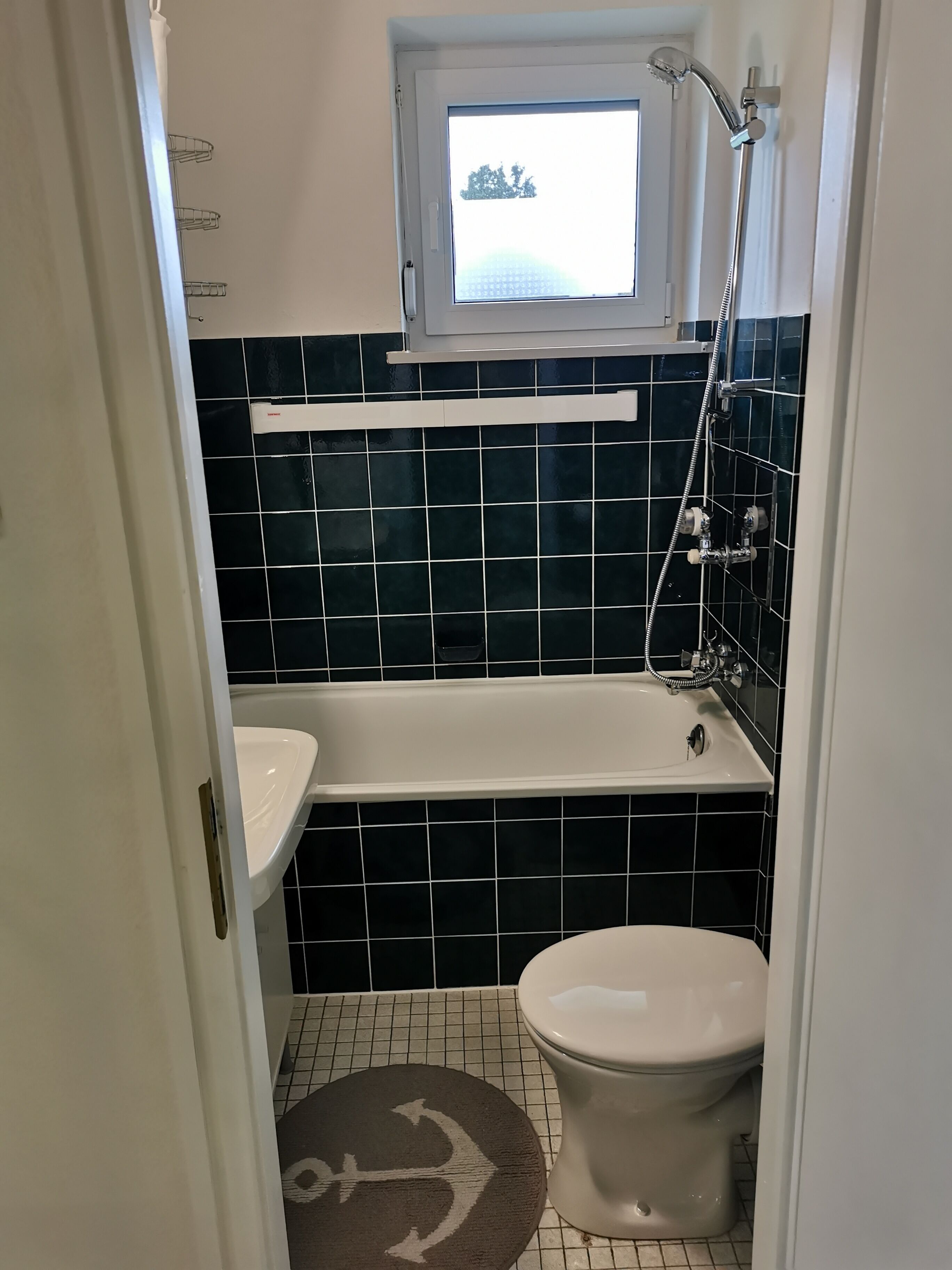 A small bathroom with a bathtub, a toilet, and a window above the sink.