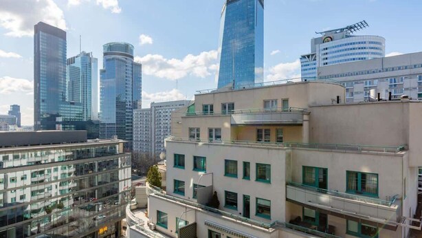 Un paisaje urbano con edificios modernos de gran altura y una mezcla de estilos arquitectónicos, incluyendo un prominente rascacielos de vidrio y un edificio con fachada curva.