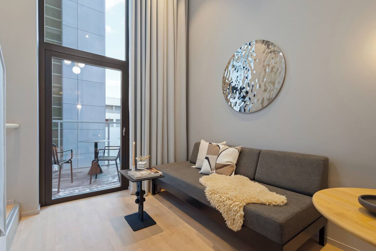 A modern living room with a grey sofa, a round wall art piece, and a wooden table.