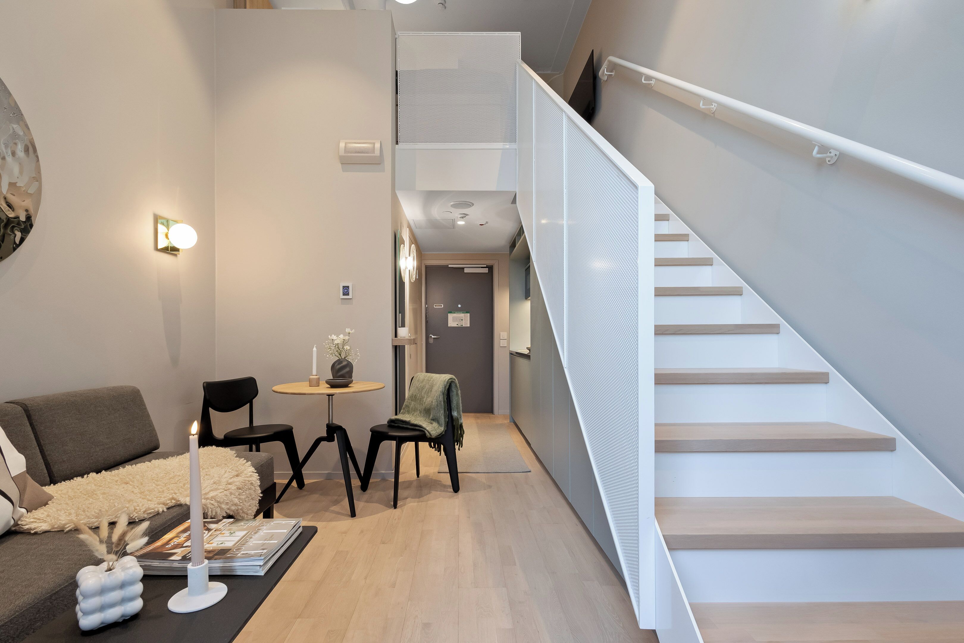Ein modernes Interieur mit einer Treppe, einem Essbereich inklusive Tisch und Stühlen sowie einer Couch.