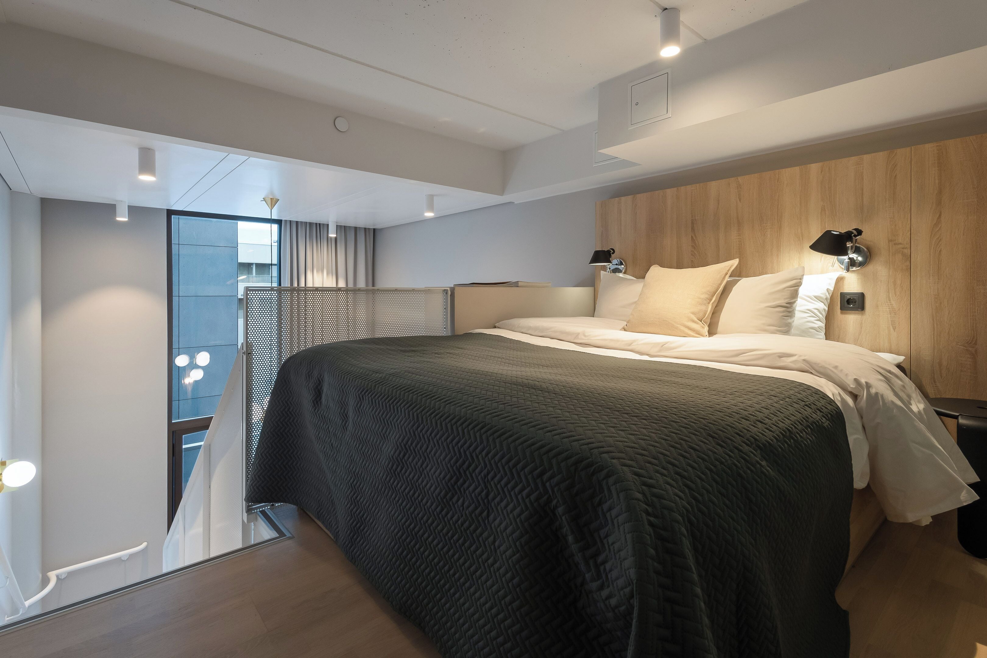 Ein modernes Schlafzimmer mit einem großen Bett, einem Holzkopfende und Blick auf einen Balkon.