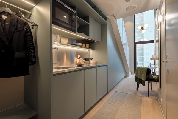 A modern kitchen with grey cabinetry, a built-in oven, and a dining area with a table and chairs.