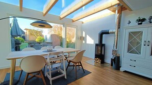 A modern kitchen with a dining area, wooden beams, a built-in stove, and a view of the outdoors. - Beachhouse with garden and sauna just 700m from the beach (Schönberg)