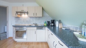 Una cocina moderna con armarios blancos, horno empotrado, campana extractora de acero inoxidable y encimera de granito.