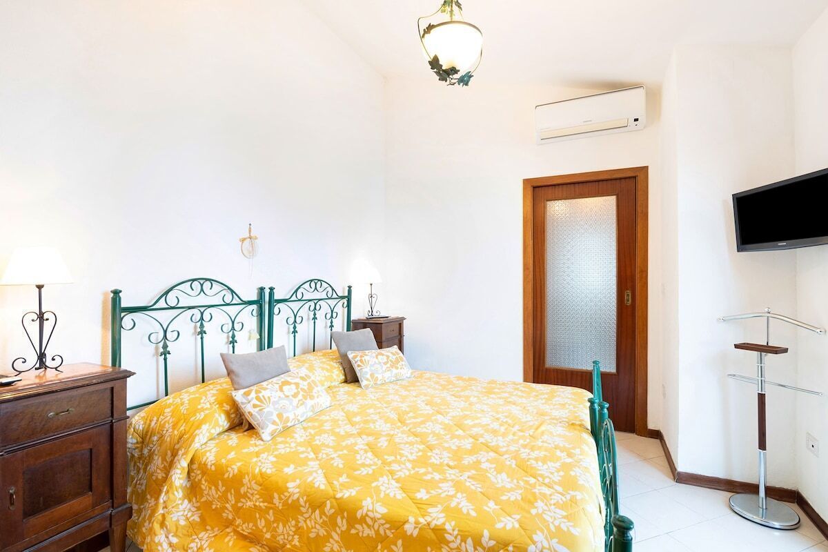 A bedroom with a bed, bedside tables, a TV, and a wardrobe.
