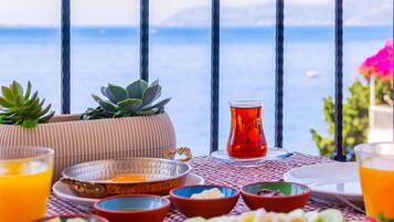 Una mesa dispuesta con diversos platos y bebidas, con vistas a un paisaje marino.