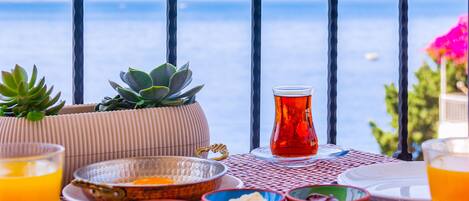 A table set with various dishes and drinks, overlooking a scenic ocean view.
