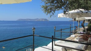 A seaside terrace with a view of the sea and distant islands, featuring a railing, a lamp post, and a covered seating area. - Kaş Old Town Hotel & Beach (Kaş)