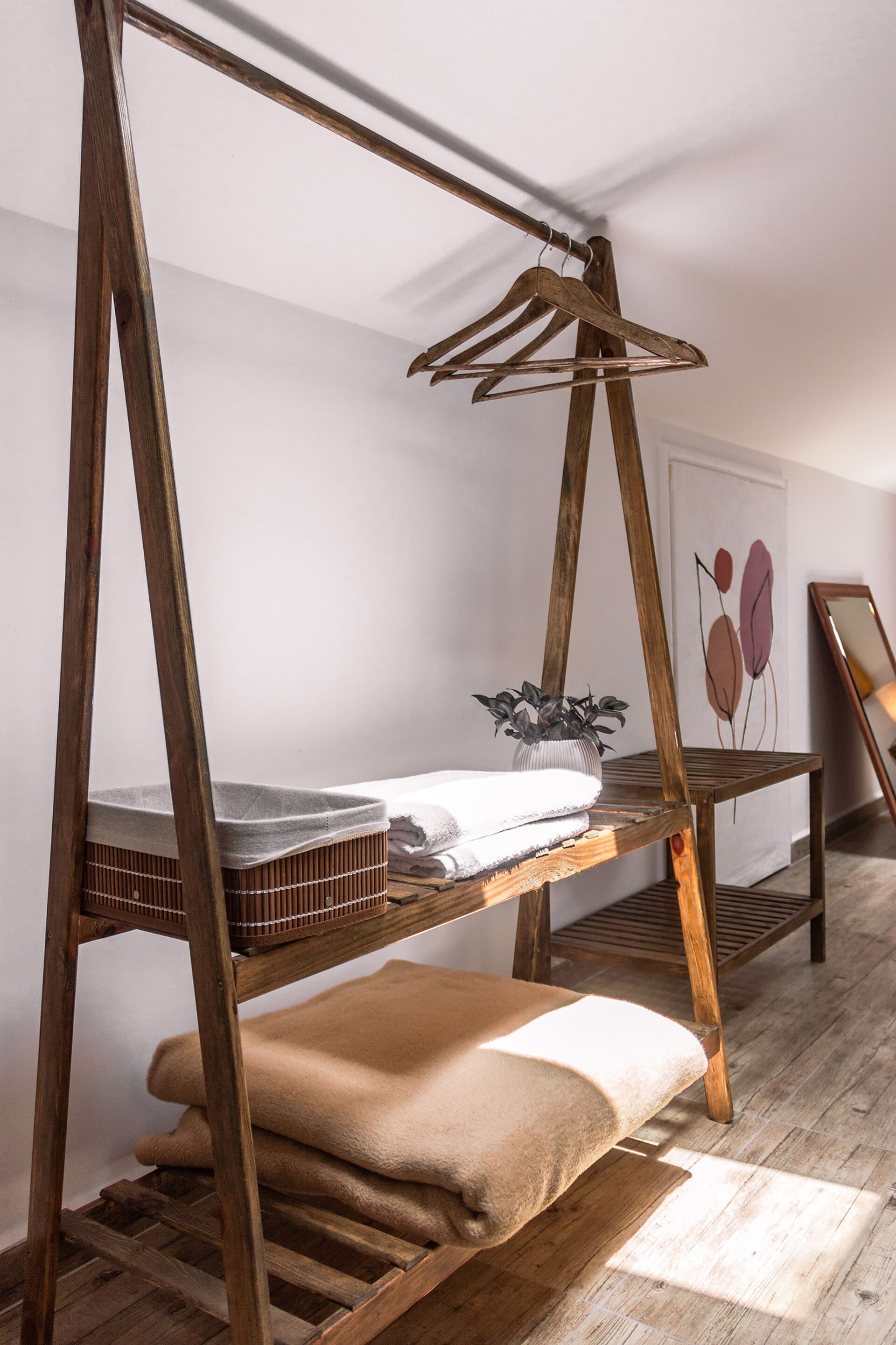 Een stapelbed met houten frame, een tafeltje met een plant en een stoel met kussen.