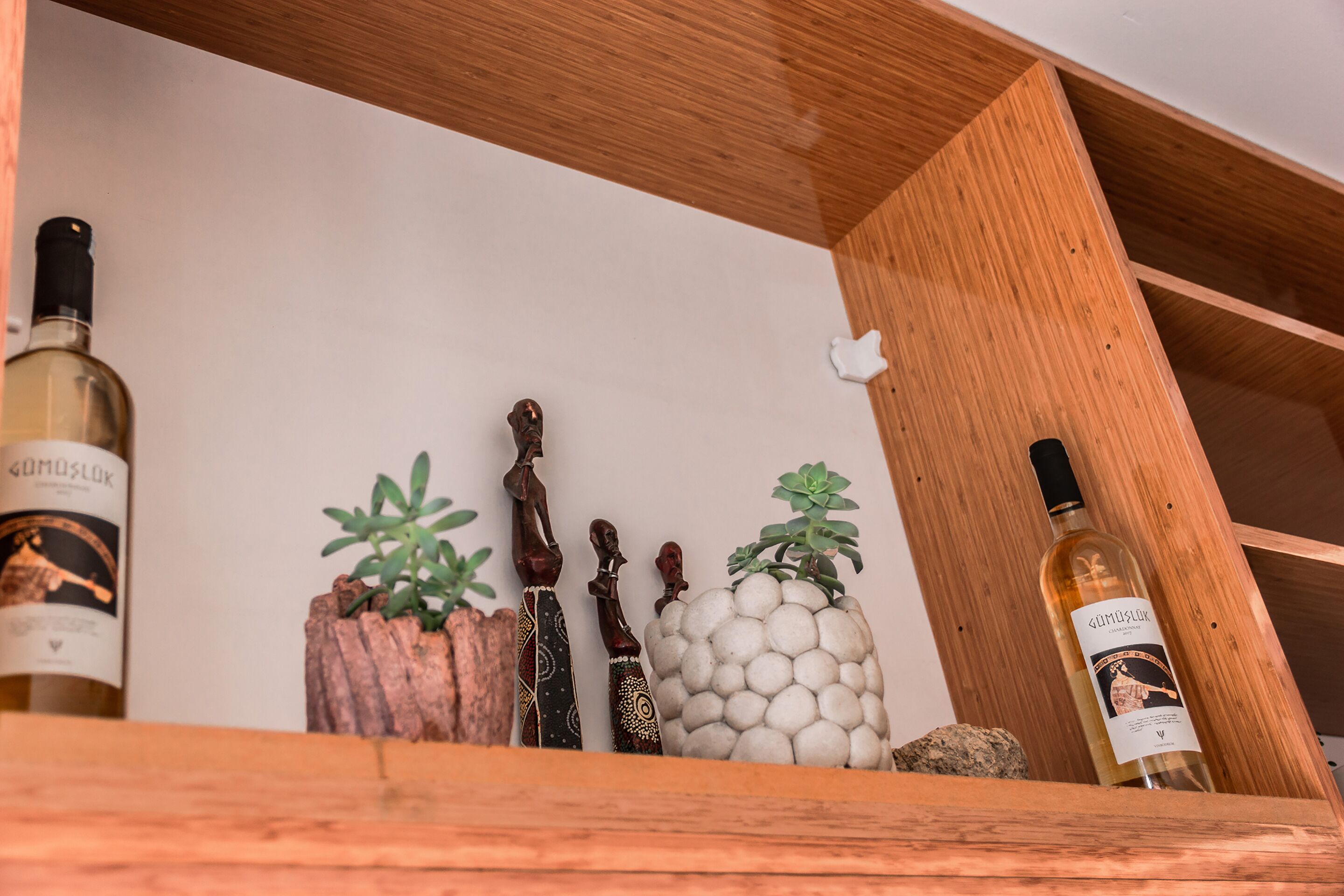 Una estantería de madera con botellas de vino y objetos decorativos.
