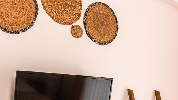 A room with a flat-screen TV mounted on the wall, a small white appliance, and a wooden ladder with towels. - Kaş Old Town Hotel & Beach (Kaş)