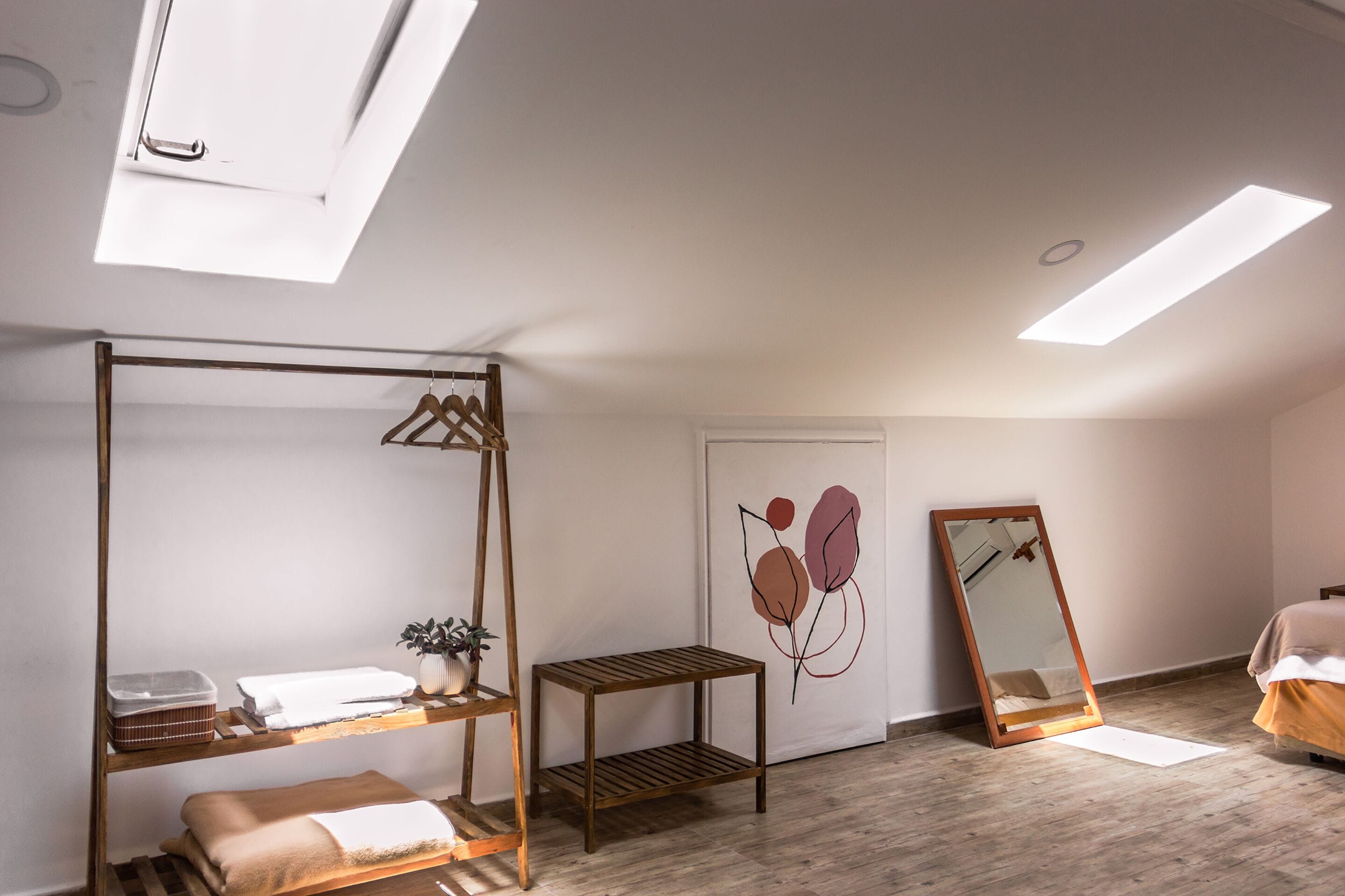 A bedroom with a bunk bed, a bedside table with a plant, a mirror, and a wall art piece.