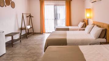 Habitación de hotel con dos camas, un estante de madera, un perchero y un balcón con cortinas.
