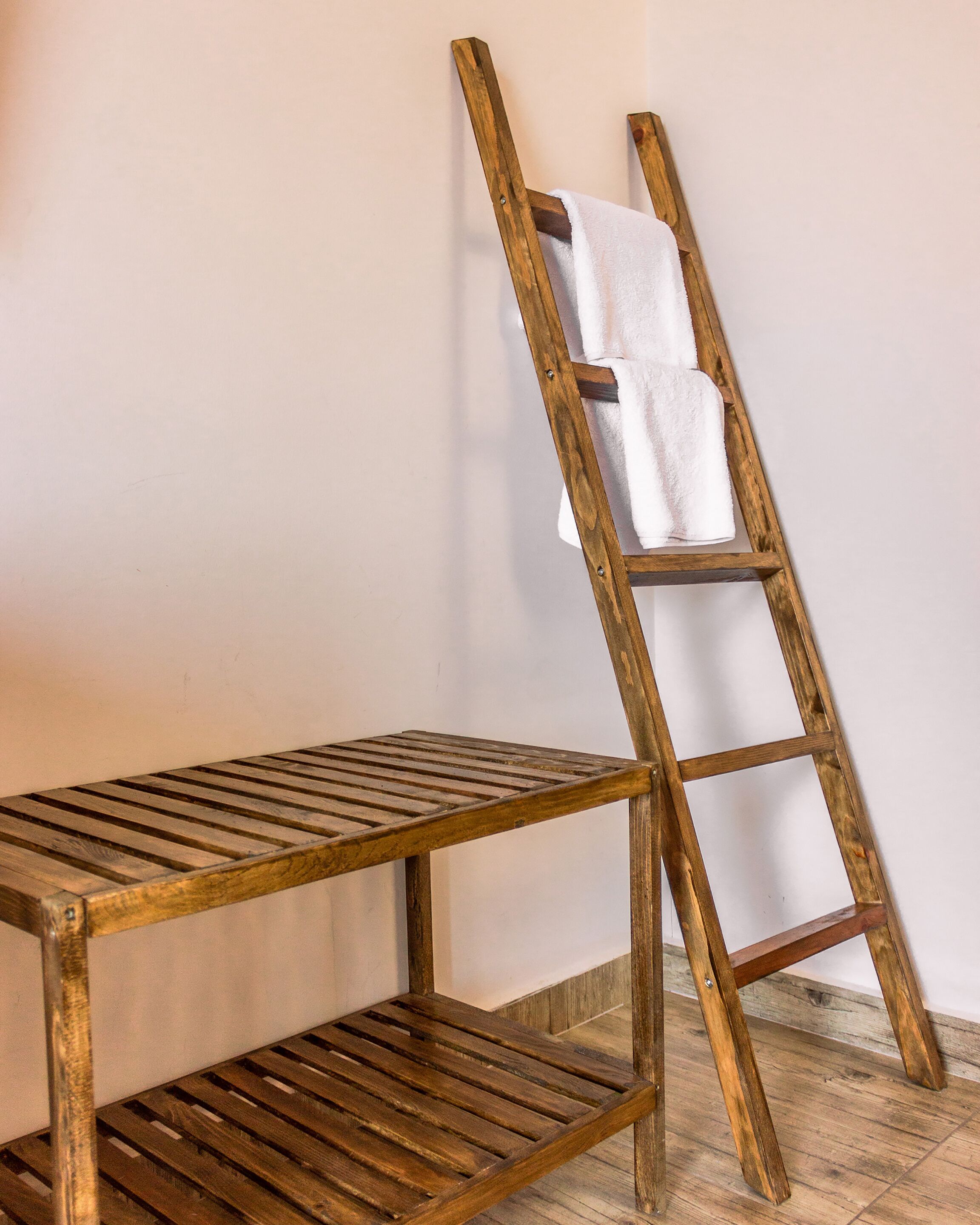 A wooden bench and a wooden ladder leaning against a wall.