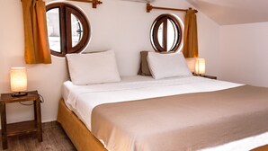 Een slaapkamer met een groot bed, twee nachtkastjes, een raam met gordijnen en een airconditioner.