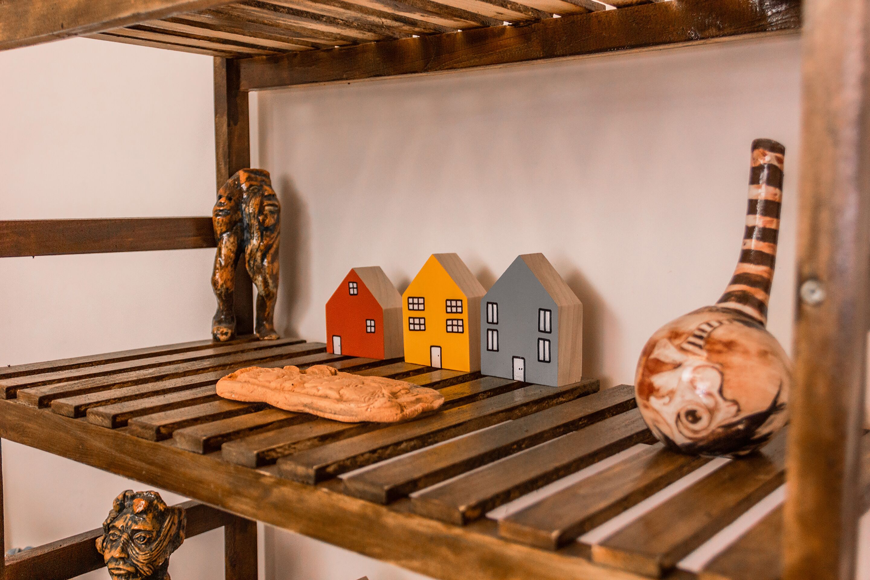 A wooden shelf with a loaf of bread, a carved wooden figure, and a vase.