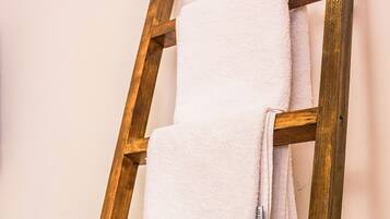 A wooden ladder with three white towels hanging on it.