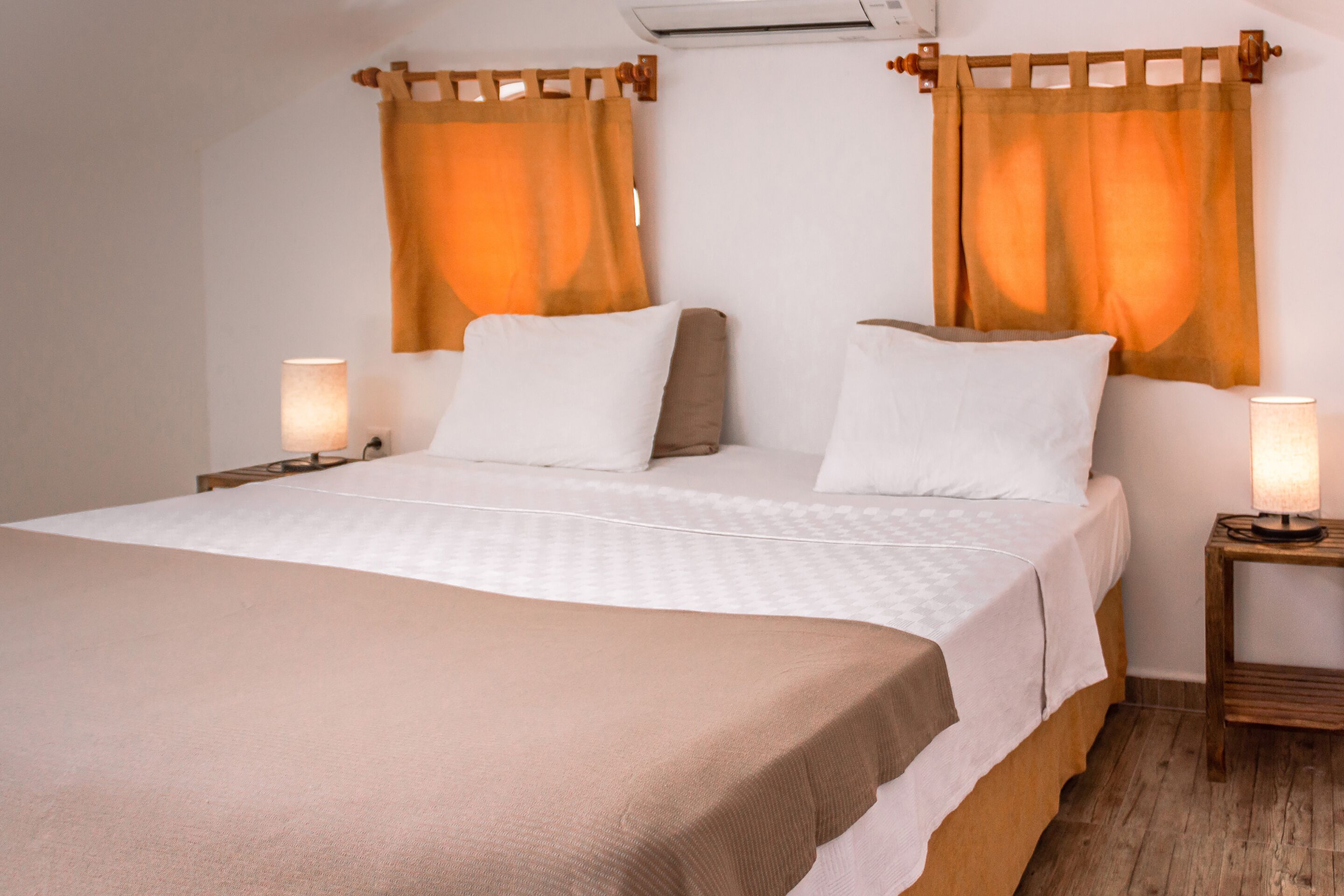 A bedroom with a large bed, two bedside tables, and curtains.