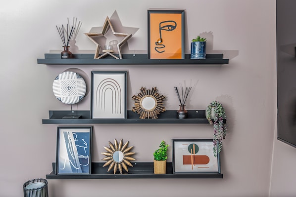 A wall with three shelves displaying various decorative items.