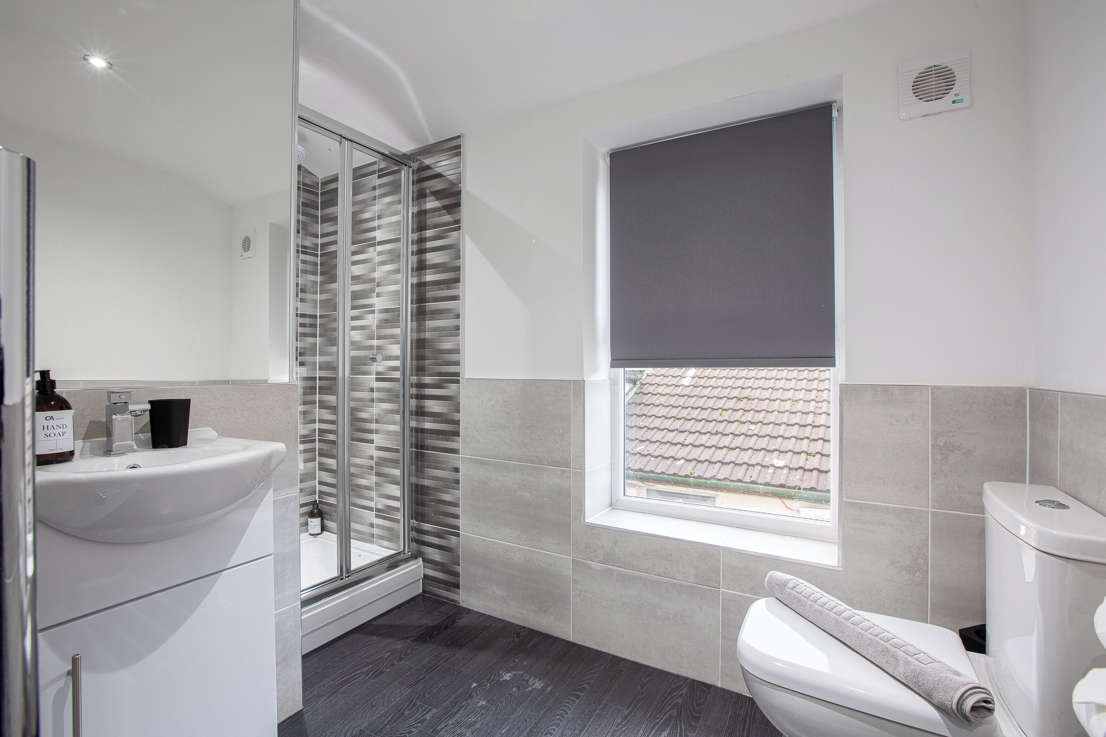 Un baño moderno con cabina de ducha de vidrio, un lavabo blanco y un inodoro.