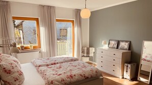 Una camera da letto con un letto, una cassettiera e una finestra con tende.