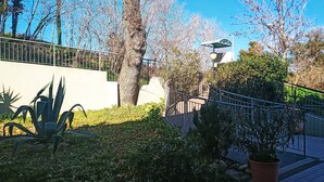 A garden area with a paved walkway, a metal railing, and various plants including a large agave plant. - Apartment with beautiful view of the hills, between Pesaro and Fano (Mombaroccio)