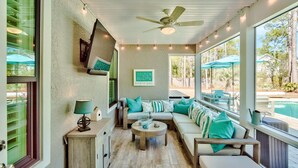 A covered outdoor seating area with a ceiling fan, string lights, and a view of a pool. - Wood Beach Retreat – Perfect 30A Location offering Easy Beach Access & Private Pool (Santa Rosa Beach)