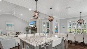 A modern kitchen with a large island, white cabinetry, and pendant lighting. - Wood Beach Retreat – Perfect 30A Location offering Easy Beach Access & Private Pool (Santa Rosa Beach)