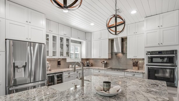 A modern kitchen with white cabinetry, stainless steel appliances, and a granite countertop. - Wood Beach Retreat – Perfect 30A Location offering Easy Beach Access & Private Pool (Santa Rosa Beach)
