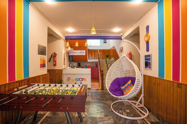 Une pièce avec une table de baby-foot, un fauteuil suspendu et un panneau sur lequel on peut lire : « Dépassez-vous. Soyez meilleur. »
