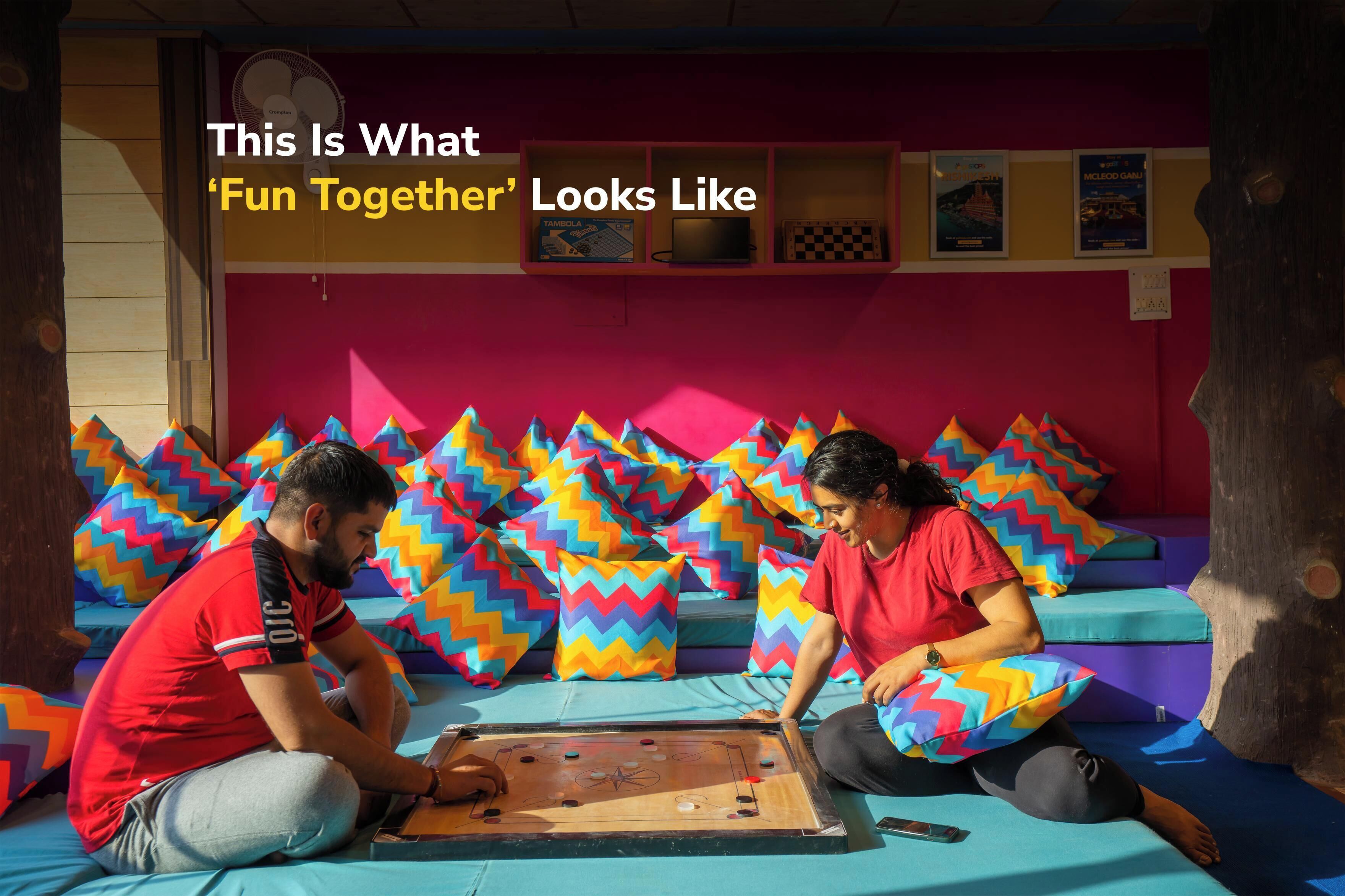 Two people playing a board game on a colorful sofa with zigzag patterned cushions.
