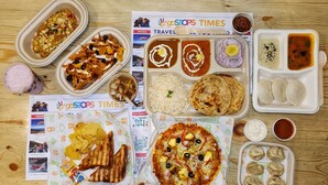 A variety of food items including nachos, rice, flatbread, pizza, and dumplings, arranged on a wooden table. - goSTOPS Kasol (Bhuntar)