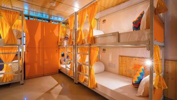 Une chambre avec des lits superposés, des rideaux orange et un plafond en bois.