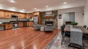 Una cocina amplia con armarios de madera, una chimenea de piedra y un comedor con mesa y sillas.
