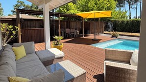 Un'area esterna coperta con piscina, mobili in vimini e un pontile in legno.
