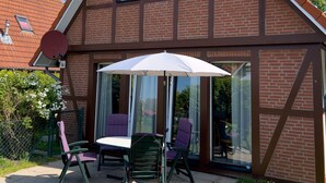 A two-story house with a sloped roof, a satellite dish, and a patio with outdoor furniture.