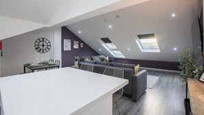 En moderne loftlejlighed med spiseplads, sofa og ovenlys.