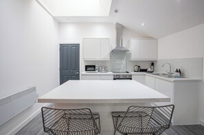 A modern kitchen with white cabinetry, a central island, and a built-in microwave.