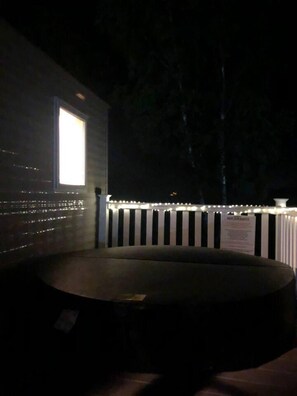 Ein schwach beleuchteter Außenbereich mit einer runden Sitzecke und einem weißen Zaun mit Lichterketten.