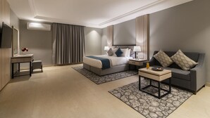 Een moderne hotelkamer met een bed, nachtkastjes, een bank en een televisie.