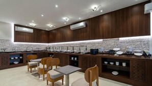 Een moderne keuken met houten lambrisering, een buffetopstelling en zitplaatsen voor gasten.