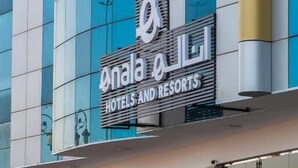 Een modern hotelgebouw met een bord waarop staat ‘Onala Hotels and Resorts’.