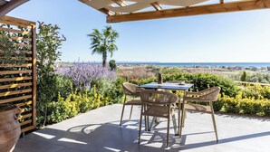 An outdoor patio with a table and chairs, a pergola, and a view of the sea. - Akrolithos luxury suites (Nea Propontida)