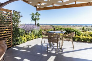 An outdoor patio with a table and chairs, a pergola, and a view of the sea. - Akrolithos luxury suites (Nea Propontida)