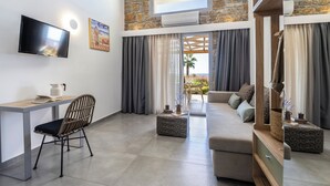 A modern living room with a TV, a sofa, a chair, and a desk. - Akrolithos luxury suites (Nea Propontida)