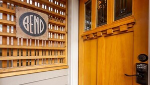 A wooden door with a keypad lock and a sign that reads "BEND" on a lattice panel.