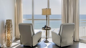 Habitación con dos sillones reclinables orientados a un ventanal grande con vista al mar. Una lámpara de pie se ubica entre los sillones.