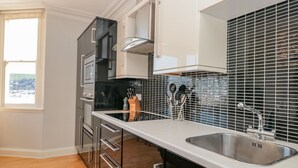 A modern kitchen with stainless steel appliances, a black tiled backsplash, and a large window. - River View (Dartmouth)