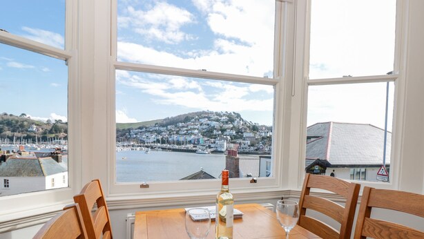 A wooden table with two chairs, a bottle of wine, and two wine glasses. - River View (Dartmouth)