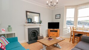 A living room with a fireplace, a television, a dining table, and a view of the harbor. - River View (Dartmouth)